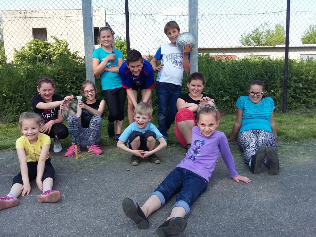 Zdjęcie przedstawia dzieci pozujące do zdjęcia w plenerze ze sprzętami sportowymi.