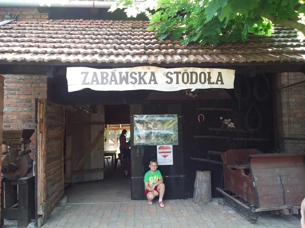 Zdjęcie przedstawia chłopca pozującego do zdjęcia w miejscowości Zabawa przy obiekcie Zabawska Stodoła