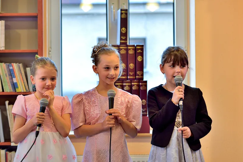 Zdjęcie przedstawia trzy dziewczynki śpiewające piosenkę na dzień Matki