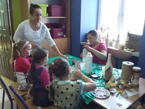 Zdjęcie przedstawia dzieci oraz opiekunów z placówki podczas zajęć manualnych, podczas których dzieci robiły ciekawe ozdoby.