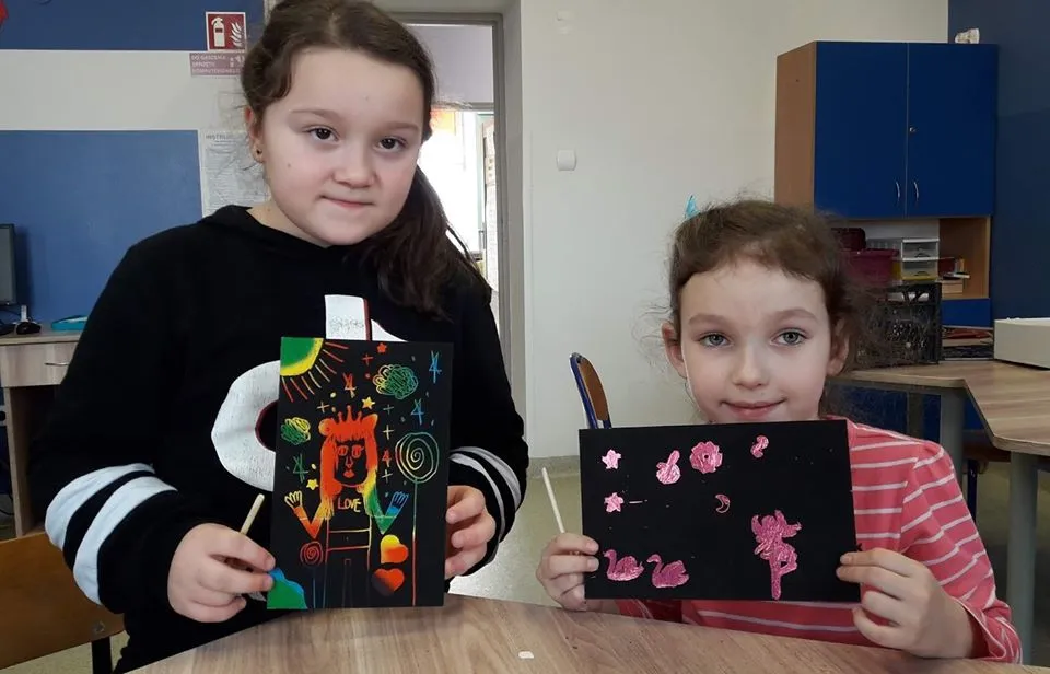 Obraz przedstawia ostatnie zrealizowane zajęcia artystyczne oraz edukacyjne dla dzieci. Na zdjęciu możemy ujrzeć wychowanków SPWD wraz z swoimi pracami, wykonanymi poprzez wydrapywanie.