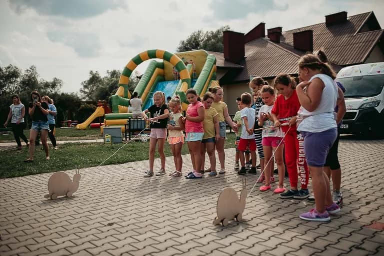 Obraz przedstawia wychowanków uczestniczących w różnego rodzaju konkursach, konkurencjach czy zabawach zorganizowanych przez animatorów.