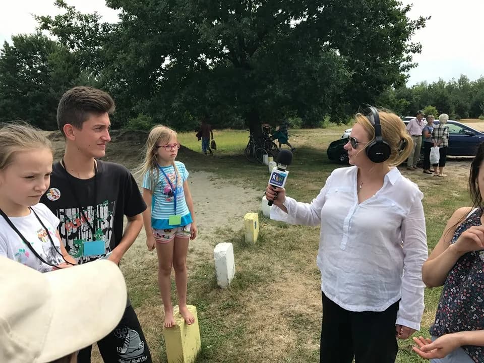 Zdjęcie przedstawia dzieci z placówki podczas pikniku w towarzystwie dziennikarki z radia RDN.